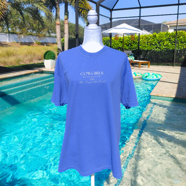 This Cowgirls Coastal Beach Club Graphic Tee is the perfect blend of western charm and summer style! This blue tee features a minimal front text and a fun beachy western graphic on the back—designed for trend-lovers and sunshine-chasers. Great for pairing with denim shorts, cowboy boots, or a trucker hat for the full cowgirl vibe. For that oversized, slouchy look, size up!