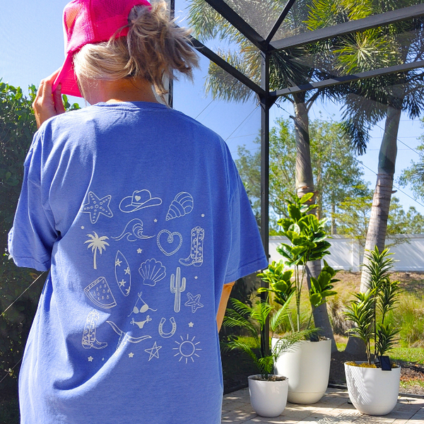 This Cowgirls Coastal Beach Club Graphic Tee is the perfect blend of western charm and summer style! This blue tee features a minimal front text and a fun beachy western graphic on the back—designed for trend-lovers and sunshine-chasers. Great for pairing with denim shorts, cowboy boots, or a trucker hat for the full cowgirl vibe. For that oversized, slouchy look, size up!