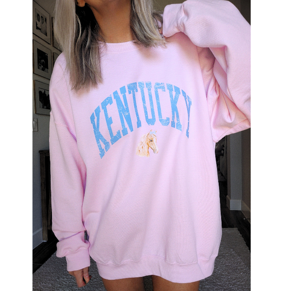 Stay cozy and stylish with our Kentucky sweatshirt, available in light pink and white! Featuring a cute coquette preppy horse with a bow, this distressed design is perfect for any horse lover or cowgirl. Ideal for a Kentucky derby outfit or as a gift, size up for an oversized fit. Order now and show off your love for all things western!