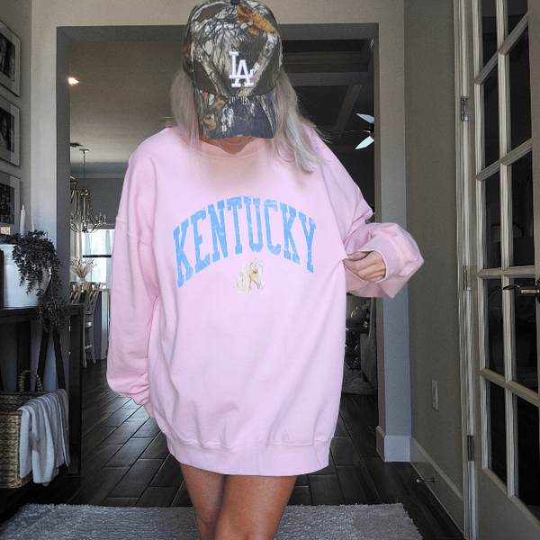 Stay cozy and stylish with our Kentucky sweatshirt, available in light pink and white! Featuring a cute coquette preppy horse with a bow, this distressed design is perfect for any horse lover or cowgirl. Ideal for a Kentucky derby outfit or as a gift, size up for an oversized fit. Order now and show off your love for all things western!