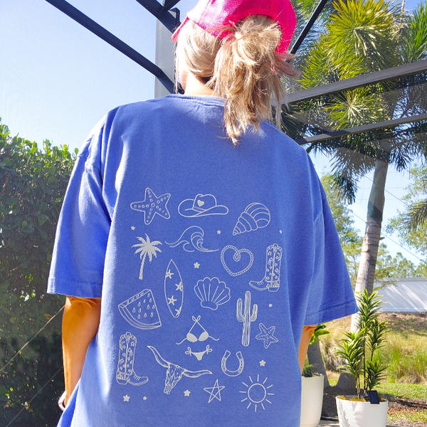 This Cowgirls Coastal Beach Club Graphic Tee is the perfect blend of western charm and summer style! This blue tee features a minimal front text and a fun beachy western graphic on the back—designed for trend-lovers and sunshine-chasers. Great for pairing with denim shorts, cowboy boots, or a trucker hat for the full cowgirl vibe. For that oversized, slouchy look, size up!