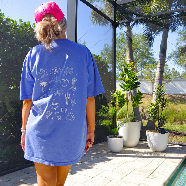 This Cowgirls Coastal Beach Club Graphic Tee is the perfect blend of western charm and summer style! This blue tee features a minimal front text and a fun beachy western graphic on the back—designed for trend-lovers and sunshine-chasers. Great for pairing with denim shorts, cowboy boots, or a trucker hat for the full cowgirl vibe. For that oversized, slouchy look, size up!