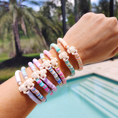 The Preppy Turtle Bracelet is perfect for summer! This eye-catching accessory features colorful Heishi clay beads and stone turtle bead to create an ocean-inspired look. It's perfect for stacking or gifting to someone special. With its unique design and mix of colors, this stretch bracelet is sure to stand out!