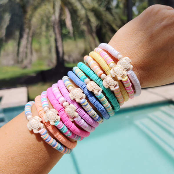 The Preppy Turtle Bracelet is perfect for summer! This eye-catching accessory features colorful Heishi clay beads and stone turtle bead to create an ocean-inspired look. It's perfect for stacking or gifting to someone special. With its unique design and mix of colors, this stretch bracelet is sure to stand out!