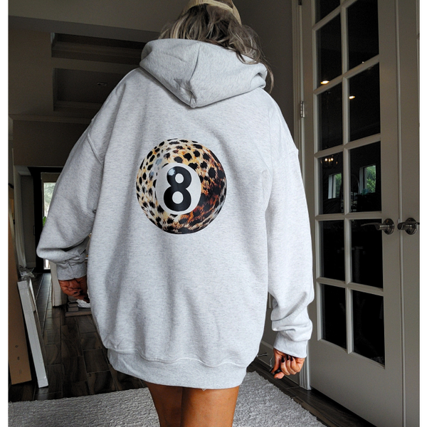 Stay stylish and on-trend with our 8 Ball Hoodie. Stand out from the crowd with a unique leopard print eight ball design that brings a touch of y2k fashion to your wardrobe. This preppy hoodie features a lucky symbol, perfect for bringing good luck to your day. For an oversized fit size up for a comfortable and streetwear-inspired look.