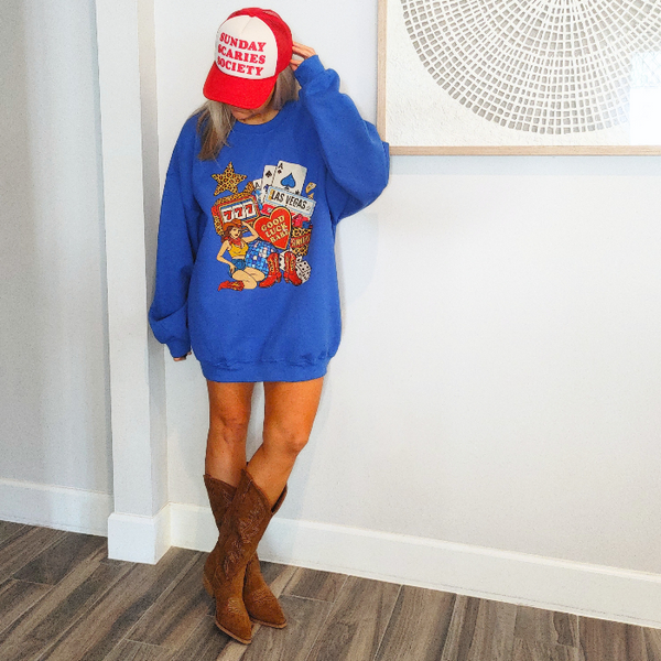Turn up the lucky vibes with this bold and retro-inspired Las Vegas graphic sweatshirt. Designed in a vibrant royal blue, this cozy pullover features the ultimate “Good Luck Babe” casino theme—complete with slot machine sevens, cowgirl art, leopard-print star, poker cards, and classic Western boots. It’s the perfect mix of vintage charm, playful style, and standout color.