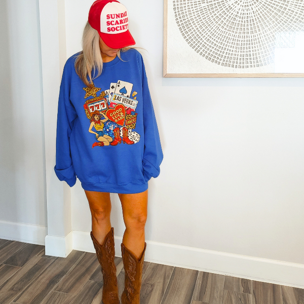 Turn up the lucky vibes with this bold and retro-inspired Las Vegas graphic sweatshirt. Designed in a vibrant royal blue, this cozy pullover features the ultimate “Good Luck Babe” casino theme—complete with slot machine sevens, cowgirl art, leopard-print star, poker cards, and classic Western boots. It’s the perfect mix of vintage charm, playful style, and standout color.