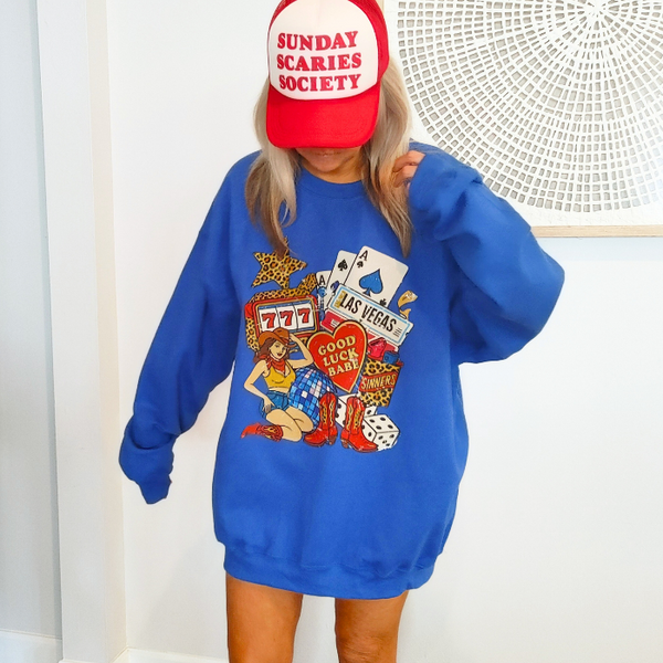 Turn up the lucky vibes with this bold and retro-inspired Las Vegas graphic sweatshirt. Designed in a vibrant royal blue, this cozy pullover features the ultimate “Good Luck Babe” casino theme—complete with slot machine sevens, cowgirl art, leopard-print star, poker cards, and classic Western boots. It’s the perfect mix of vintage charm, playful style, and standout color.