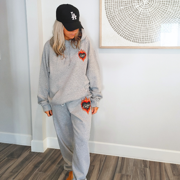 This matching Cowboys flame sweatshirt and sweatpants set delivers bold western style with all-day comfort. Featuring a fiery heart “Cowboys” graphic, this gray lounge set is perfect for cozy days, casual outings, travel, or effortless cowgirl street style.