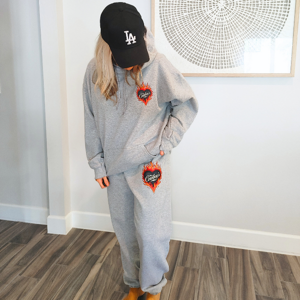 This matching Cowboys flame sweatshirt and sweatpants set delivers bold western style with all-day comfort. Featuring a fiery heart “Cowboys” graphic, this gray lounge set is perfect for cozy days, casual outings, travel, or effortless cowgirl street style. 