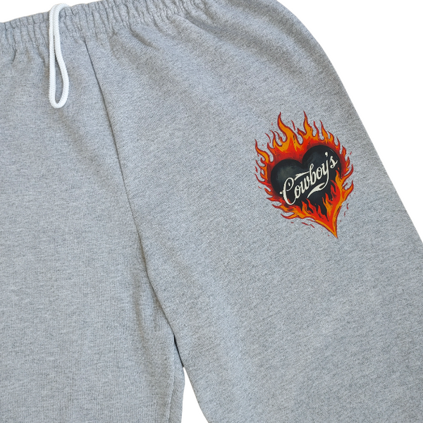 Bring bold western energy to your everyday wardrobe with these Cowboys flame sweatpants. Featuring a striking flaming heart “Cowboys” graphic, these gray jogger-style sweatpants are designed for laid-back comfort with a statement edge. They have an oversized fit for that relaxed, effortlessly look. They feature a drawstring elastic waistband and elastic cuffs for all-day comfort and an easy fit.