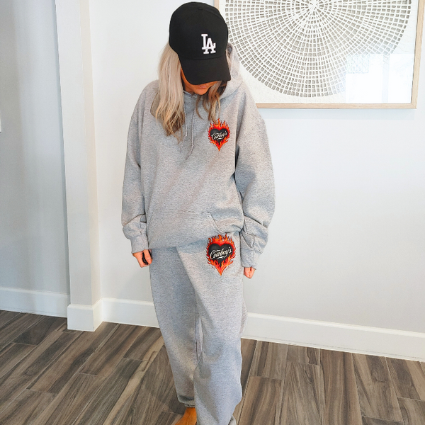 This matching Cowboys flame sweatshirt and sweatpants set delivers bold western style with all-day comfort. Featuring a fiery heart “Cowboys” graphic, this gray lounge set is perfect for cozy days, casual outings, travel, or effortless cowgirl street style.