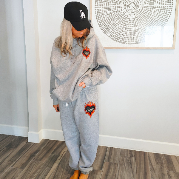 This matching Cowboys flame sweatshirt and sweatpants set delivers bold western style with all-day comfort. Featuring a fiery heart “Cowboys” graphic, this gray lounge set is perfect for cozy days, casual outings, travel, or effortless cowgirl street style.