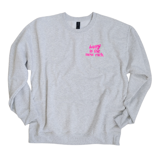 Bring all the good vibes with this cozy “Happy Is the New Rich” smiley face sweatshirt. Featuring a bold neon-pink front chest quote and an oversized happy face graphic on the back, this crewneck is designed to make every outfit feel a little brighter. This soft, comfy unisex crewneck makes the perfect gift and for everyday wear, this is your new go-to layer for errands, lounging, weekend adventures, and everything in between. Pair it with our matching sweatpants (sold separately) for the full set. 