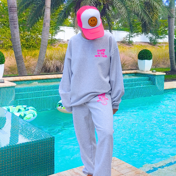 Bring all the happy vibes with this trendy “Happy Is the New Rich” loungewear set. Designed with a bold neon-pink graphic and a preppy, on-trend style, this matching sweatshirt and sweatpants outfit is the perfect blend of cozy comfort and feel-good energy. The sweatshirt is soft, relaxed, and features the neon-pink “Happy Is the New Rich” design on the front with a large smiley face graphic on the back. If you want that oversized, stylish, slouchy look, we recommend sizing up for the perfect relaxed fit. T