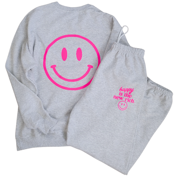 Bring all the good vibes with this cozy “Happy Is the New Rich” smiley face sweatshirt. Featuring a bold neon-pink front chest quote and an oversized happy face graphic on the back, this crewneck is designed to make every outfit feel a little brighter. This soft, comfy unisex crewneck makes the perfect gift and for everyday wear, this is your new go-to layer for errands, lounging, weekend adventures, and everything in between. Pair it with our matching sweatpants (sold separately) for the full set. 