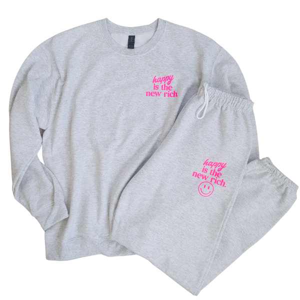 Bring all the good vibes with this cozy “Happy Is the New Rich” smiley face sweatshirt. Featuring a bold neon-pink front chest quote and an oversized happy face graphic on the back, this crewneck is designed to make every outfit feel a little brighter. This soft, comfy unisex crewneck makes the perfect gift and for everyday wear, this is your new go-to layer for errands, lounging, weekend adventures, and everything in between. Pair it with our matching sweatpants (sold separately) for the full set. 