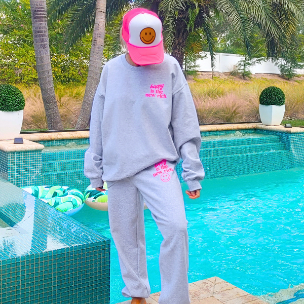 Bring all the happy vibes with these trendy “Happy Is the New Rich” smiley face sweatpants. Designed in a classic ash gray and featuring the saying “Happy Is the New Rich” along with a bold neon-pink happy face graphic, these joggers are the perfect mix of comfy, cute, and on-trend. With a relaxed, oversized fit and an elastic waistband, they’re your new everyday go-to. They pair perfectly with our matching sweatshirt (sold separately) to complete the loungewear set — and they also make the perfect gift!