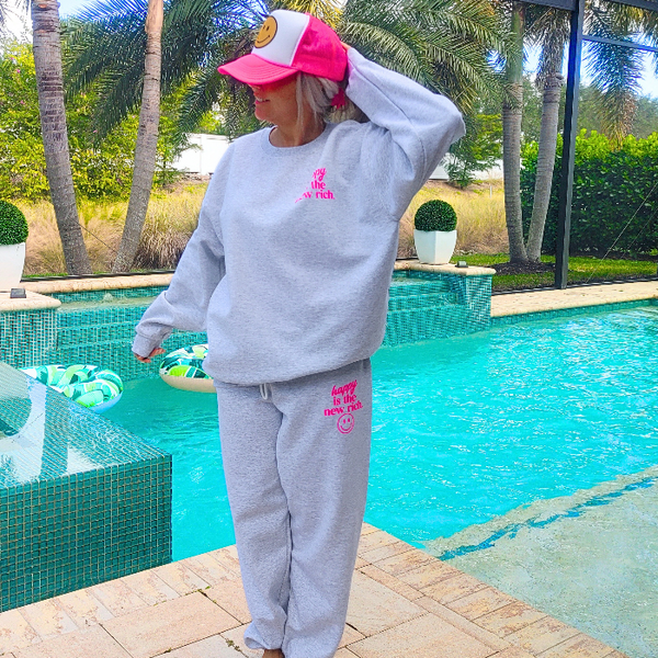 Bring all the happy vibes with these trendy “Happy Is the New Rich” smiley face sweatpants. Designed in a classic ash gray and featuring the saying “Happy Is the New Rich” along with a bold neon-pink happy face graphic, these joggers are the perfect mix of comfy, cute, and on-trend. With a relaxed, oversized fit and an elastic waistband, they’re your new everyday go-to. They pair perfectly with our matching sweatshirt (sold separately) to complete the loungewear set — and they also make the perfect gift!