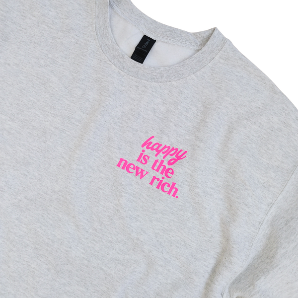 Bring all the good vibes with this cozy “Happy Is the New Rich” smiley face sweatshirt. Featuring a bold neon-pink front chest quote and an oversized happy face graphic on the back, this crewneck is designed to make every outfit feel a little brighter. This soft, comfy unisex crewneck makes the perfect gift and for everyday wear, this is your new go-to layer for errands, lounging, weekend adventures, and everything in between. Pair it with our matching sweatpants (sold separately) for the full set. 