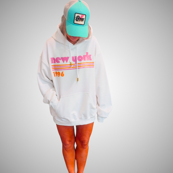 This New York Hoodie is the perfect blend of retro style and everyday comfort. Featuring a distressed New York graphic with vibrant pink and orange stripes, metallic gold beaded drawstrings, and a cozy unisex fit, it's a statement hoodie made for city lovers, travelers, and anyone who loves a bold vintage-inspired aesthetic. Size up 1–2 sizes for a cozy oversized look.