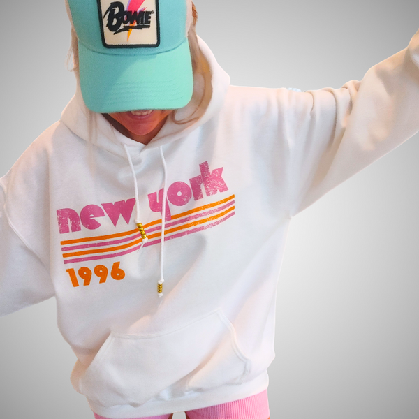 This New York Hoodie is the perfect blend of retro style and everyday comfort. Featuring a distressed New York graphic with vibrant pink and orange stripes, metallic gold beaded drawstrings, and a cozy unisex fit, it's a statement hoodie made for city lovers, travelers, and anyone who loves a bold vintage-inspired aesthetic. Size up 1–2 sizes for a cozy oversized look.