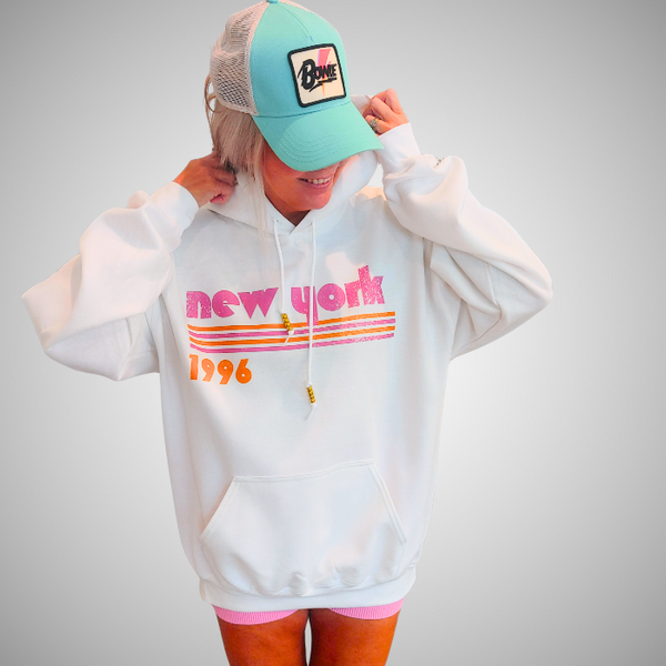 This New York Hoodie is the perfect blend of retro style and everyday comfort. Featuring a distressed New York graphic with vibrant pink and orange stripes, metallic gold beaded drawstrings, and a cozy unisex fit, it's a statement hoodie made for city lovers, travelers, and anyone who loves a bold vintage-inspired aesthetic. Size up 1–2 sizes for a cozy oversized look.