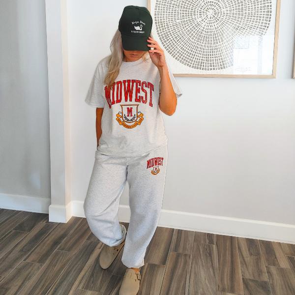 These Midwest Logo Sweatpants are the ultimate blend of comfort and casual oversized relaxed fit for a trendy streetwear look. Featuring a distressed varsity-inspired graphic that matches the sweatshirt and t-shirt in the collection, these ash gray joggers have a drawstring elastic waistband for adjustable comfort & are perfect for lounging, travel, errands, or creating a coordinated Midwest set look.