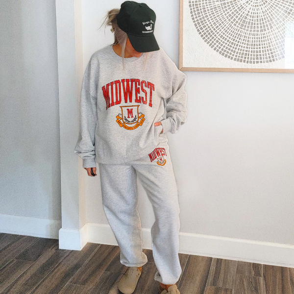 These Midwest Logo Sweatpants are the ultimate blend of comfort and casual oversized relaxed fit for a trendy streetwear look. Featuring a distressed varsity-inspired graphic that matches the sweatshirt and t-shirt in the collection, these ash gray joggers have a drawstring elastic waistband for adjustable comfort & are perfect for lounging, travel, errands, or creating a coordinated Midwest set look.