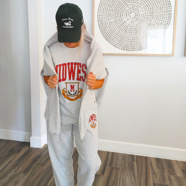 This Midwest Sweatshirt is the perfect blend of cozy comfort and classic collegiate style. Featuring a distressed varsity-inspired graphic on a soft ash gray crewneck, this unisex sweatshirt delivers an effortless retro look that's perfect for everyday wear, game days, travel, or lounging in comfort. Size up for an oversized sweatshirt look.