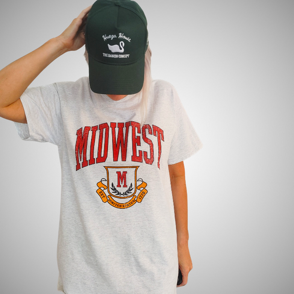 This Retro Midwest Graphic Tee brings classic collegiate style and effortless comfort together in one timeless design. Featuring a distressed varsity-inspired "Midwest" graphic on a soft 100% cotton Gildan unisex tee, it's perfect for anyone who loves vintage aesthetics, casual streetwear, and laid-back everyday fashion. Size up for a trendy oversized look.