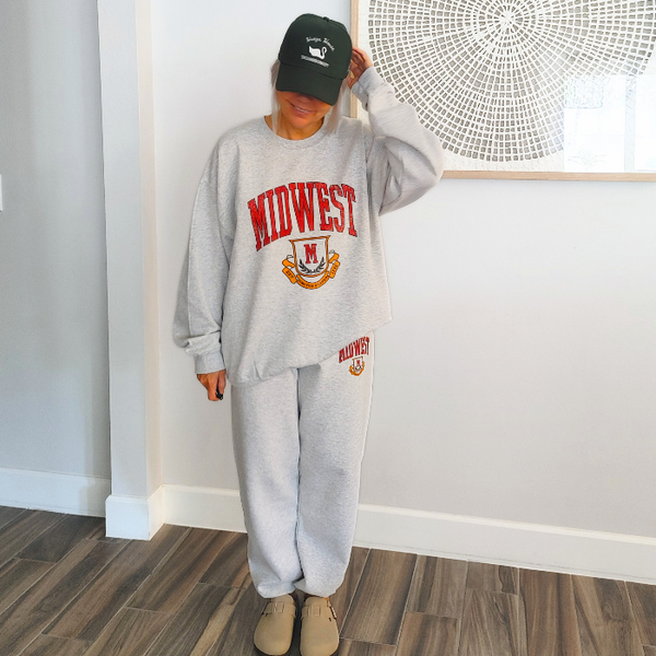This Midwest Sweatshirt is the perfect blend of cozy comfort and classic collegiate style. Featuring a distressed varsity-inspired graphic on a soft ash gray crewneck, this unisex sweatshirt delivers an effortless retro look that's perfect for everyday wear, game days, travel, or lounging in comfort. Size up for an oversized sweatshirt look.