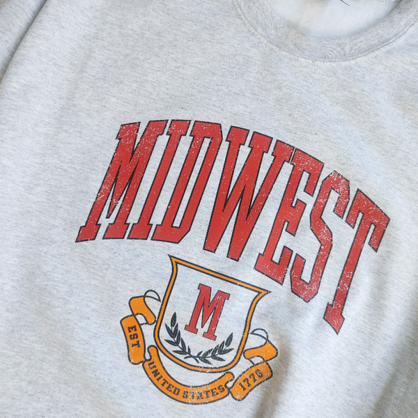 This Midwest Sweatshirt is the perfect blend of cozy comfort and classic collegiate style. Featuring a distressed varsity-inspired graphic on a soft ash gray crewneck, this unisex sweatshirt delivers an effortless retro look that's perfect for everyday wear, game days, travel, or lounging in comfort. Size up for an oversized sweatshirt look.