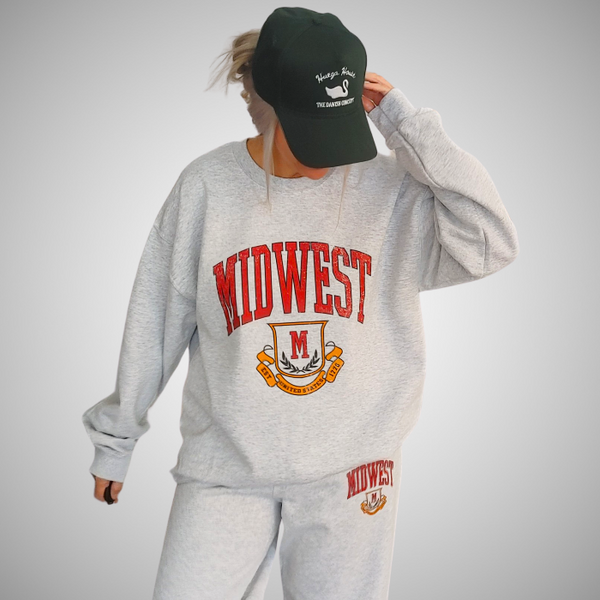 This Midwest Sweatshirt and Sweatpants Set combines cozy comfort with classic collegiate style. Featuring a distressed varsity-inspired Midwest graphic on a matching ash gray crewneck and jogger set, this outfit is perfect for travel days, casual weekends, running errands, or relaxing in ultimate comfort. Sweatpants feature a relaxed oversized fit, and for an oversized fit size up in our crewneck. Matching Midwest graphic t-shirt sold separately.